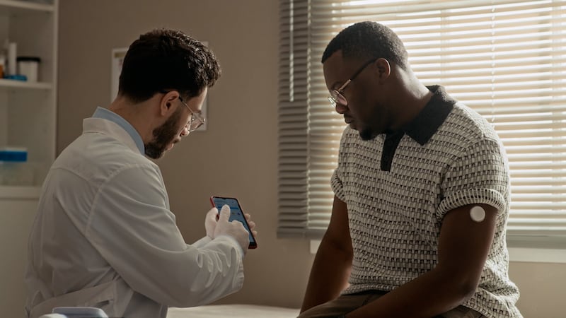 A doctor and man looking at a phone screen